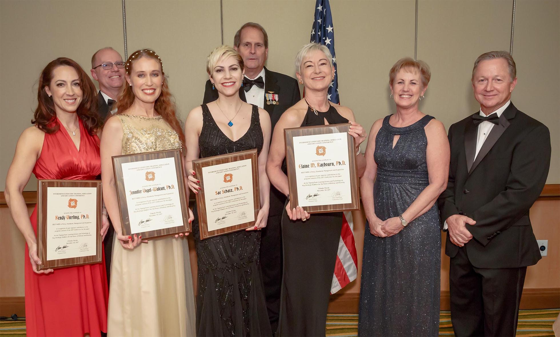 The authors receiving their "Best Policy Subcommittee Paper" award, left to right: Kendy Vierling, Ph.D., Jennifer "JJ" Vogel-Walcutt, Ph.D., Sae Schatz, Ph.D., and Elaine M. Raybourn, Ph.D. with the IITSEC 2017 Leadership.